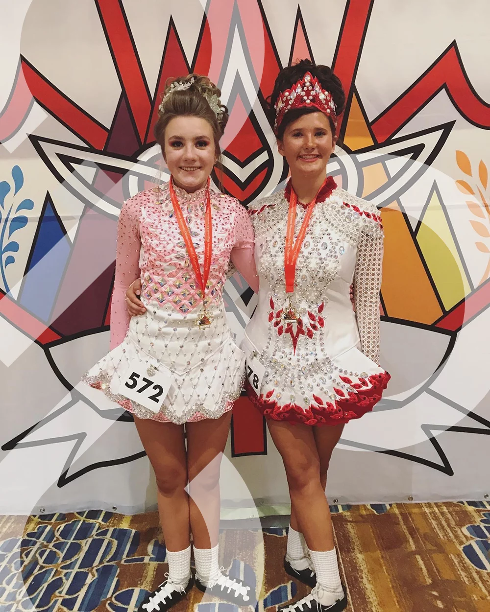Two teeange girls in sparkly Irish dance solo dresses stand in front of a logo shaped like the Canadian Maple leaf. Both are wearing medals shaped like the same Maple Leaf logo. The IDTANA logo is woven throughout.